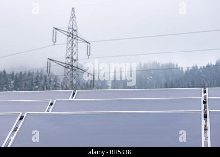 Three rows of solar panels placed on the roof of the house. In the background you can see an element of the high-voltage power network - a power pole. Stock Photo