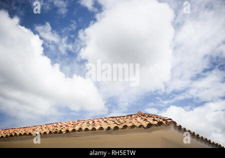 Cloudy blu skies creating negative space for copy over a typical terracotta tiled roof of a white house in Villa de Leyva, Colombia Stock Photo