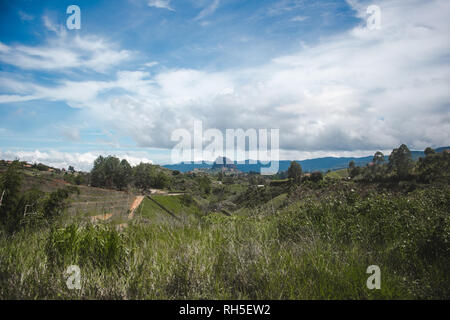 Colombian Antioquia countryside with the Guatapé Piedra del Peñol rock visible behind the rolling green hills Stock Photo