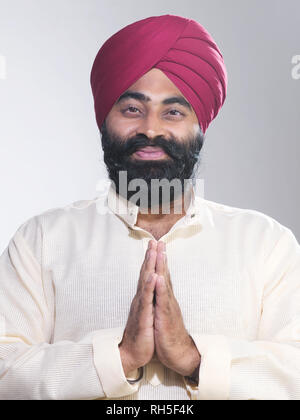 PORTRAIT OF A SIKH SARDAR MAN WITH HANDS FOLDED IN A TRADITIONAL INDIAN GREETING Stock Photo