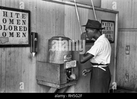 Negro drinking at Colored water cooler in streetcar terminal