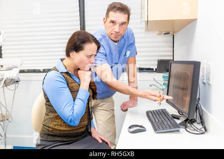 Dentist showing worried patient her teeth x-ray. Discussing issues Stock Photo