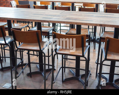 Row of retro style wooden bar stools and modern wooden tables in cafe. Stock Photo