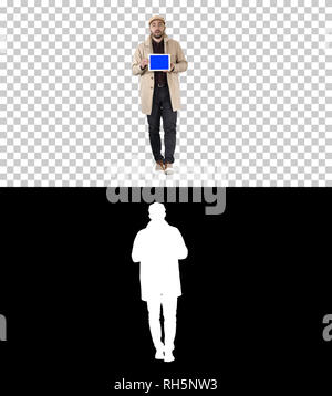 Young man walking, talking and showing digital tablet with blue screen mockup, Alpha Channel Stock Photo