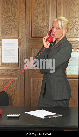 Businesswoman standing and talking on telephone in formal office setting Stock Photo