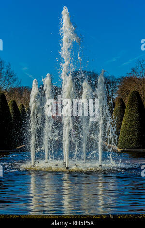 Fountain in operation with reflection in the water with trees in the background, wonderful sunny day with a blue sky in the Netherlands Stock Photo