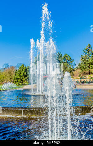 Two fountains in function in a park with trees in the background, wonderful sunny day with a blue sky in the Netherlands Holland Stock Photo