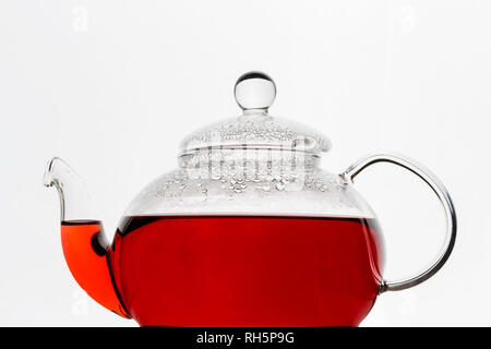 Transparency glass teapot with red hibiscus karkade tea at white background. Close up, menu, free space Stock Photo