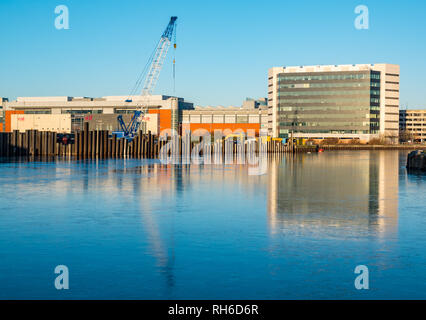 Leith, Edinburgh, Scotland, United Kingdom, 1st February 2019. UK Weather: Unusual phenomenon of a frozen water in Albert Dock Basin in Leith Harbour with buildings at Ocean Terminal and the construction site with a crane reflected in the icy surface of the water Stock Photo