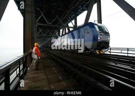 (190201) -- JIUJIANG, Feb. 1, 2019 (Xinhua) -- Bridge workers wait for the passing of a train on the Jiujiang Yangtze River Bridge, a double-decked road-rail truss bridge and an important section of Beijing-Kowloon (Jingjiu) Railway in Jiujiang, east China's Jiangxi Province, Jan. 31, 2019. Safety inspections have been strengthened to secure transportation during the 2019 Spring Festival travel rush. (Xinhua/Ding Bo) Stock Photo