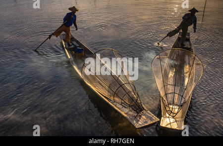 Lake Inle/ Myanmar- January 12,2019: two traditional Intha fishermen using one leg oaring method in long boat in the early morning on Lake Inle