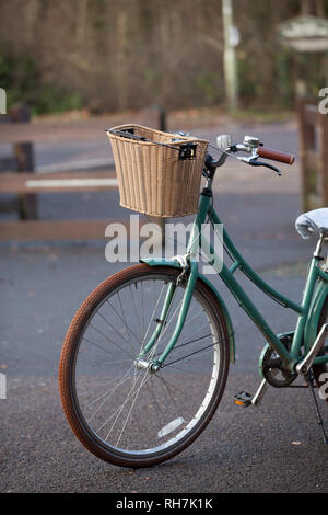 Green ladies bicycle with wicker basket on front Stock Photo