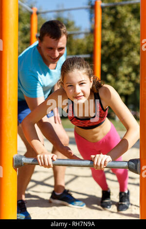 Sporty preteen girl doing push-ups on gymnastics bar during workout ...