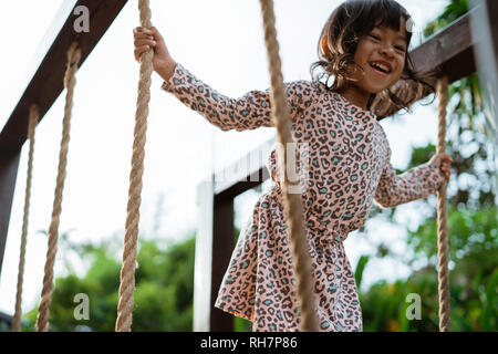 close up of asian little girl smilling when hold the rope playing balance beam Stock Photo