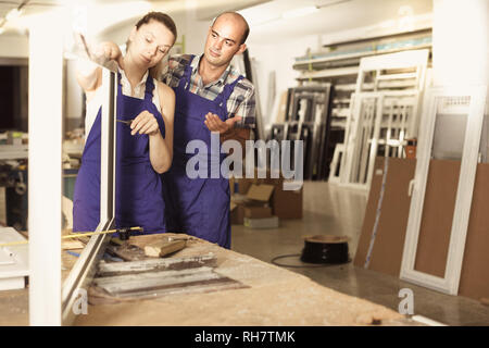 Team of two workers in blue overalls assembling pvc windows at factory Stock Photo