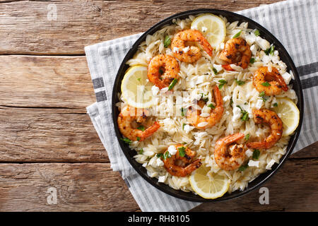Mediterranean food Pasta orzo with grilled shrimps, feta cheese and lemon close-up on a plate on the table. horizontal top view from above Stock Photo
