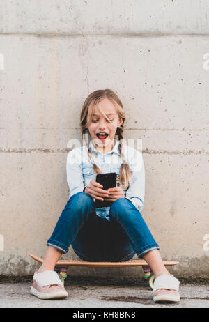 Kid using mobile phone with skate Stock Photo