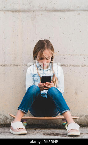 Kid using mobile phone with skate Stock Photo