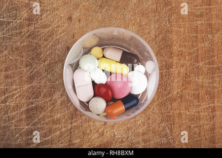 Medical drug pills in plastic container on wooden table view from above Stock Photo