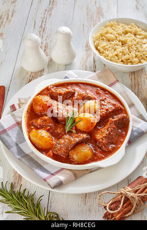 spicy stifado - flavorful beef stew with onion bulbs, cinnamon and spices in a bowl served with orzo pasta, vertical view from above, close-up Stock Photo
