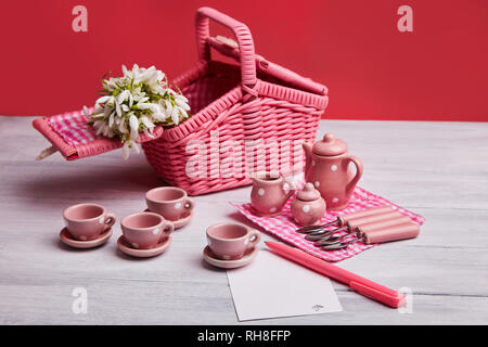 Picnic card with table setting and snowdrops, silverware, pink white checked napkin, white rustic wooden board background, empty space for text. Stock Photo