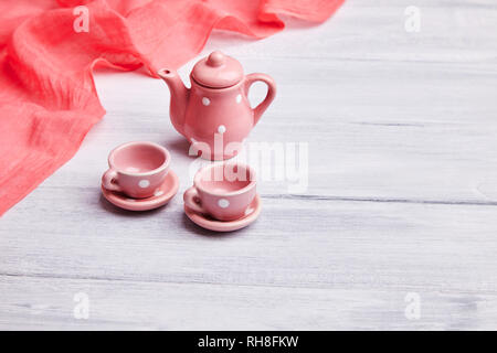 Two pink ceramic tea cups and a teapot on the table. Place for text. Invitation card Stock Photo