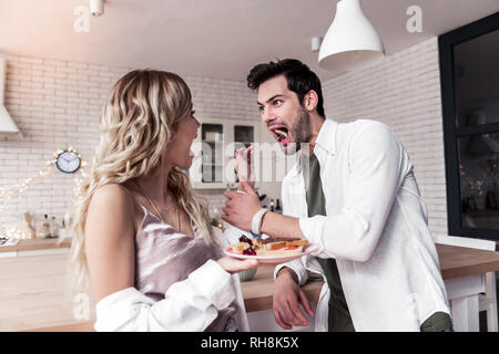 Dark-haired bearded man in a white shirt and his wife having fun at the breakfast Stock Photo