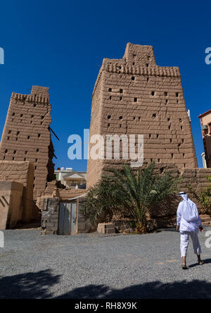 Saudi man passing in front of traditional old mud houses, Najran Province, Najran, Saudi Arabia Stock Photo