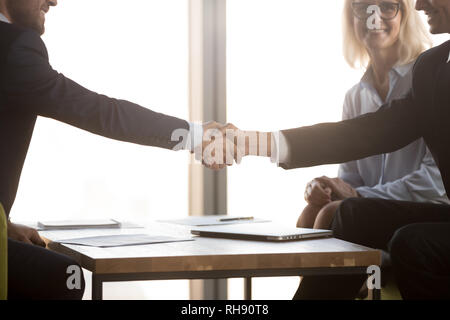 Satisfied business partners in suits shake hands, close up view Stock Photo