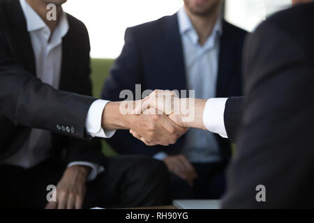 Two businessmen in suits shake hands at meeting, close up Stock Photo