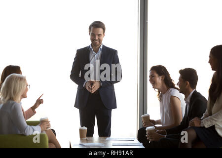 Friendly male leader having fun conversation with office workers team Stock Photo