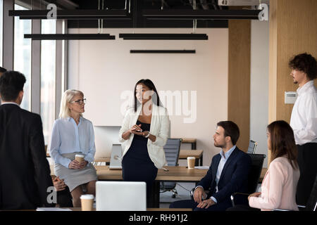 Serious asian coach speaking at diverse corporate group meeting Stock Photo