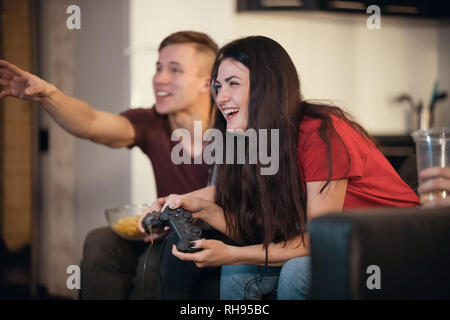 Company of young friends spending time together. A young woman having fun playing with a joystick