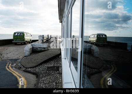 Volkswagen Camper Van parked up at Freshwater bay and its reflection in big window, Isle of Wight, England, UK. Stock Photo