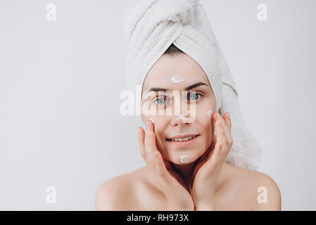 Skin care. A beautiful and smiling woman using a skin care product, moisturizer or lotion taking care of her dry complexion. Causing moisturizer cream Stock Photo