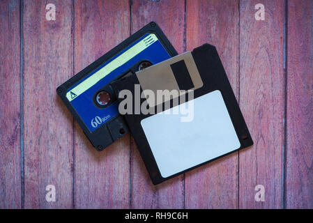 Antique pc diskettes and cassettes on a brown wooden background Stock Photo