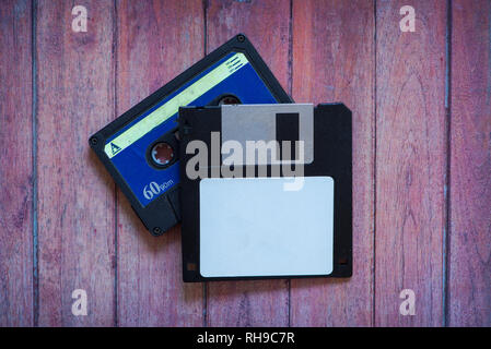 Antique pc diskettes and cassettes on a brown wooden background Stock Photo