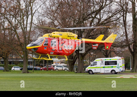An MBB/Kawasaki BK 117 rescue helicopter meets a St John's ambulance in a local park to transfer a patient to Christchurch Hospital, New Zealand Stock Photo