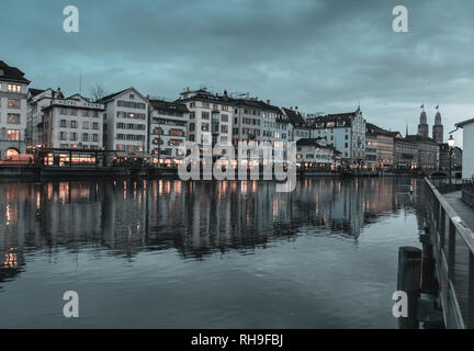 Switzerland, Zurich - January 09, 2019: view of the old town of Zurich on Limmat river with Grossmünster towers in the evening dawn Stock Photo