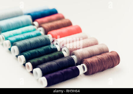 Colored sewing thread coils on white background with copy space for text Stock Photo