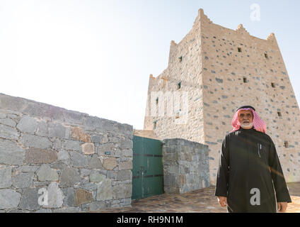 Saudi man standing in front of an old traditional stone house, Asir province, Al-Namas, Saudi Arabia Stock Photo