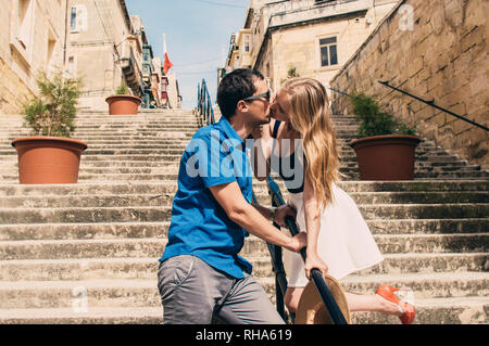 Man and woman walking and kissing on the stairs on the street, old city of the Threee Cities, Malta Stock Photo