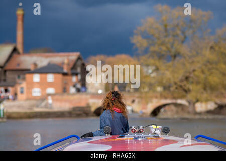 girl with red curly hair stood on front of canal boat with typical english buildings in background and fantastic light Stock Photo
