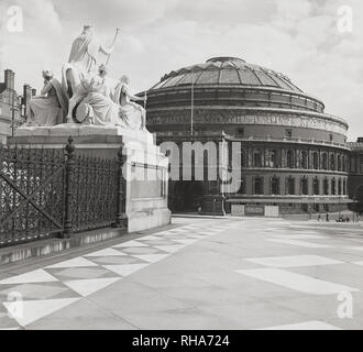 1950s, historical, view from Hyde Park, with the Albert Memorial on the left, of the Royal Albert Hall, a famous concert venue in Kensington, London, England, UK. On the notice board outside, details of  the Henry Wood Promenade Concerts. Stock Photo