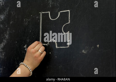Chalk hand drawing as puzzle shape on black board background Stock Photo