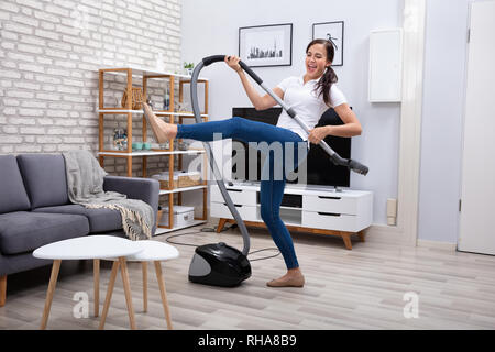 Happy Female Janitor Dancing With Vacuum Cleaner At Home Stock Photo
