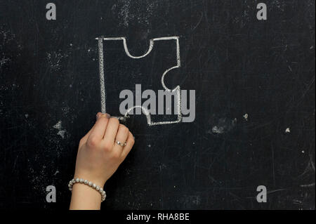 Chalk hand drawing as puzzle shape on black board background Stock Photo