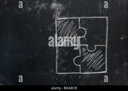 Chalk hand drawing as puzzle shape on black board background Stock Photo