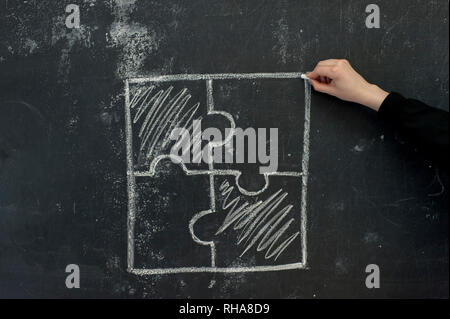 Chalk hand drawing as puzzle shape on black board background Stock Photo