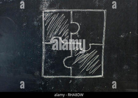 Chalk hand drawing as puzzle shape on black board background Stock Photo